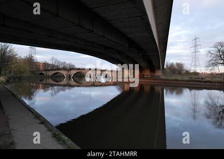 Vue de dessous une route moderne à deux voies, sur la rivière aire au Royaume-Uni. Un vieux pont de grès peut être vu en arrière-plan avec Elect Banque D'Images