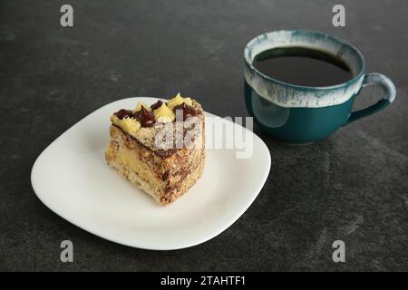 Morceau de délicieux gâteau Kyiv servi avec du café sur la table noire Banque D'Images