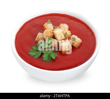 Délicieuse soupe à la crème de tomate avec croûtons et persil dans un bol isolé sur blanc Banque D'Images