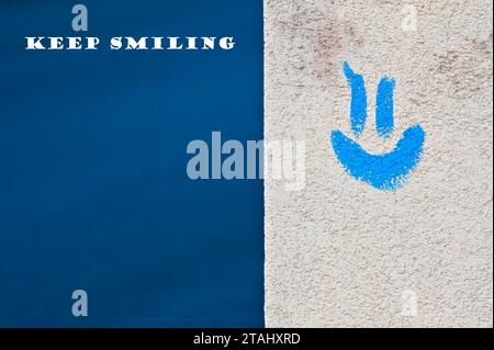 Émotion positive et concept souriant. Emoji bleu sur le bâtiment face et fond bleu. Espace de copie négatif pour le placement du texte. Garde le sourire ! Banque D'Images