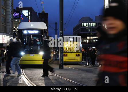 Berlin - Deutschland. Alexanderplatz, Leute Hasten über die Gleise, während eine Tram kommt. *** 24 11 2023, Berlin, Allemagne. 24 novembre 2023. Alexanderplatz, les gens se dépêchent sur les pistes pendant qu'un tramway arrive Credit : Imago/Alamy Live News Banque D'Images