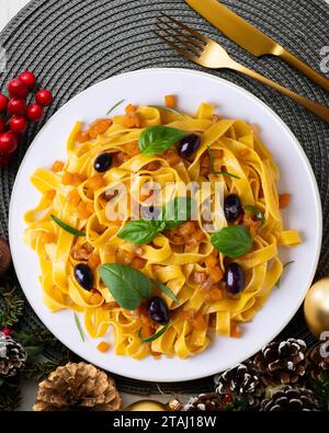 Rubans de pâtes avec citrouille sautée et olives noires. Repas de Noël servis sur une table décorée de motifs de Noël. Banque D'Images