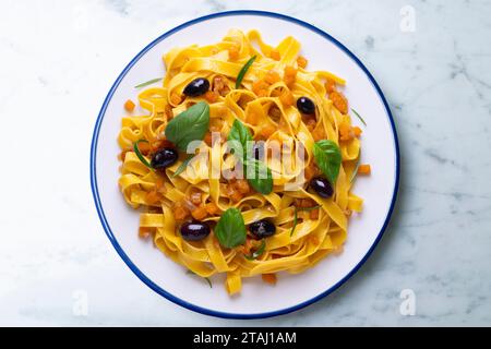 Rubans de pâtes avec citrouille sautée et olives noires. Banque D'Images