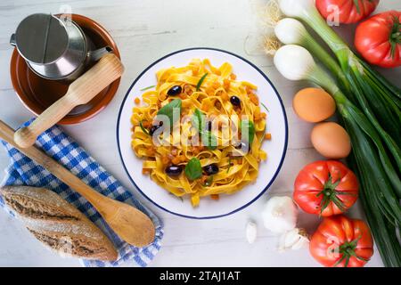 Rubans de pâtes avec citrouille sautée et olives noires. Banque D'Images