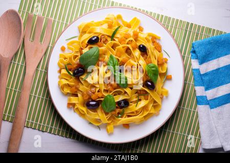 Rubans de pâtes avec citrouille sautée et olives noires. Banque D'Images