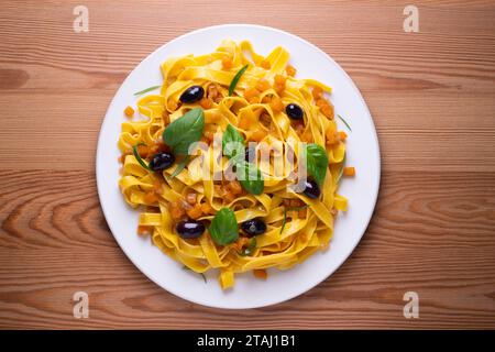 Rubans de pâtes avec citrouille sautée et olives noires. Banque D'Images