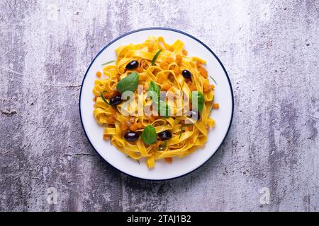 Rubans de pâtes avec citrouille sautée et olives noires. Banque D'Images