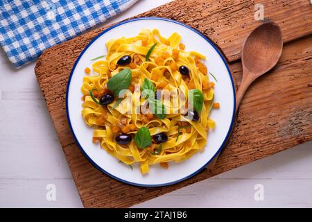 Rubans de pâtes avec citrouille sautée et olives noires. Banque D'Images