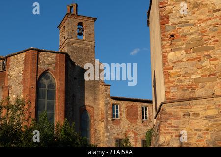 Les premiers rayons du soleil matinal frappent l'extérieur de briques vieillissantes des bâtiments à Lucignano, Toscane, Italie. Banque D'Images