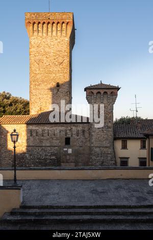 Les premiers rayons du soleil matinal frappent l'extérieur de briques vieillissantes des bâtiments à Lucignano, Toscane, Italie. Banque D'Images