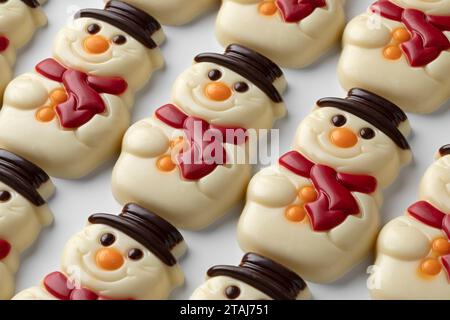 Joyeux bonhommes de neige au chocolat blanc dans les rangées sur fond blanc gros plan Banque D'Images