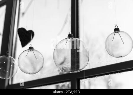Boules de verre transparentes accrochées devant une fenêtre, décoration de Noël abstraite photo noir et blanc Banque D'Images