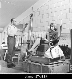 Artiste dans les années 1960 Un artiste masculin dans son atelier peint une femme assise comme modèle dans un fauteuil avec un sac à côté. 1964. Kristoffersson réf DH4 Banque D'Images
