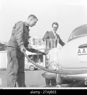 Propriétaire de voiture des années 1950 Un homme avec un homme de service dans une station-service obtient de l'aide pour remplir le réservoir. 1959 Banque D'Images