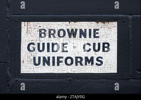 Un vieux panneau annonçant Brownie, Guide et Cub uniformes, Glasgow, Écosse, Royaume-Uni, Europe Banque D'Images