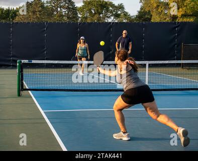 Une joueuse de pickleball retourne un tir de revers dans un match en double mixte. Banque D'Images