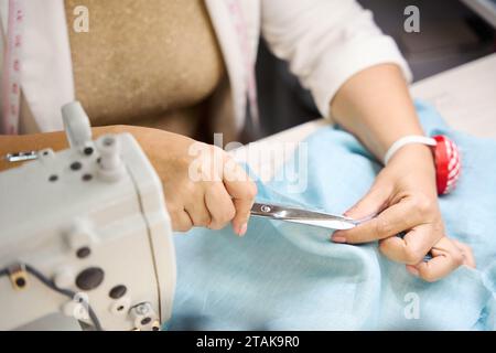 Couturière coupe les fils sur une robe avec des ciseaux Banque D'Images