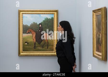 LONDRES, ROYAUME-UNI - 01 DÉCEMBRE 2023 : un membre du personnel de la galerie regarde un tableau de Jacques Laurent Agasse «Portrait équestre d'une dame, traditionnellement considérée comme Miss Mary Jane Keith (1811-1891), avec le marié de Lord Rivers et un épagneul noir» (estimation : £40 000 - 60,000) lors d'un photocall à la maison de vente Sotheby's présentant les temps forts de la Old Masters week Sales à Londres, Royaume-Uni, le 01 décembre 2023. La vente en soirée de la semaine des maîtres de décembre s'étend du début du XVe au début du XXe siècle et présente un large éventail d'œuvres remarquables de presque tous les genres. (PH Banque D'Images