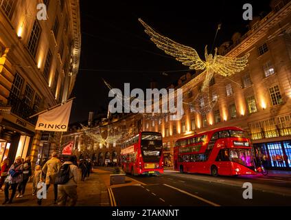 Londres, Royaume-Uni - novembre 20 2023 : Regent Street dans le centre de Londres avec deux bus rouges et des lumières de Noël au-dessus. Les gens font du shopping de Noël. Banque D'Images