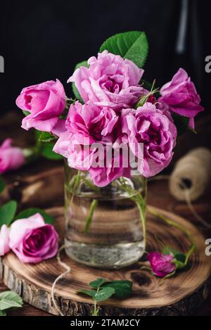 Bouquet de petites roses de jardin roses dans le vase sur la table Banque D'Images