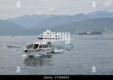 Le ferry pour passagers Topazio quitte Stresa sur le lac majeur, tandis qu'un bateau-taxi privé arrive à son poste d'amarrage. Banque D'Images