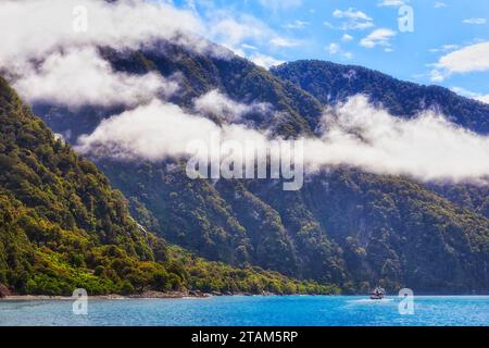 Bateau de croisière à grande échelle sous de majestueux sommets montagneux autour de Milford Sound of Fiordland en Nouvelle-Zélande. Banque D'Images