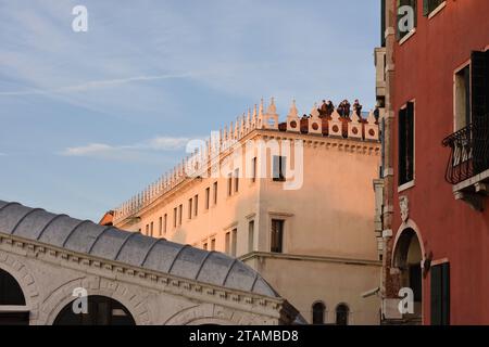 Les touristes regardent le pont du Rialto et le Grand canal pour profiter de la ligne d'horizon de Venise depuis le toit de Fondaco dei Tedeschi à l'approche du coucher du soleil. Banque D'Images