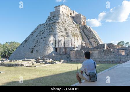 Touriste assis avec son dos regardant le Temple du Fortune Teller sur le site archéologique d'Uxmal dans le Yucatan, Mexique Banque D'Images