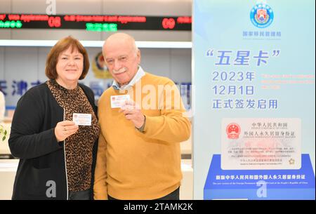 (231202) -- BEIJING, 2 déc. 2023 (Xinhua) -- les titulaires de cartes présentent leur nouvelle version de leurs cartes d'identité de résident permanent étranger au département de l'administration des entrées-sorties du bureau municipal de la sécurité publique de Tianjin, à Tianjin, dans le nord de la Chine, le 1 décembre 2023. L'Administration nationale de l'immigration (NIA) a mis en service vendredi une nouvelle version de la carte d'identité de résident permanent étranger de la République populaire de Chine. Le même jour, le premier lot de 50 nouvelles cartes a été délivré aux étrangers qualifiés dont les demandes de résidence permanente avaient été approuvées, a indiqué la NIA. Ces nouveaux titulaires de carte viennent f Banque D'Images