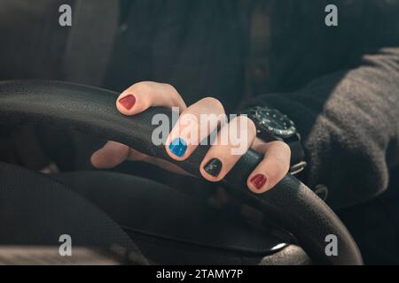 Gros plan d'une main d'homme portant une montre de luxe et tenant un volant. Foyer sélectionné. Un homme aux ongles peints. Conception de clous masculins. homme manucur Banque D'Images