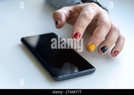 Gros plan d'un homme utilisant un téléphone intelligent mobile. Un homme avec une manucure tape sur l'écran du smartphone. Banque D'Images