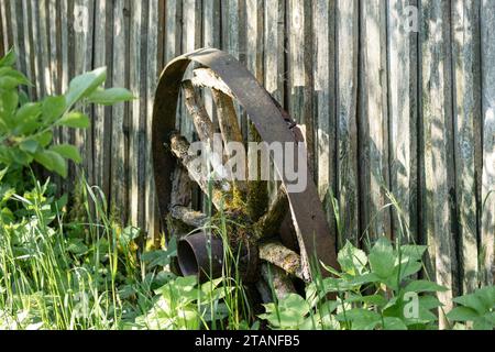 une vieille roue d'une voiture tirée par des chevaux appuyée contre un mur en bord dans l'herbe Banque D'Images