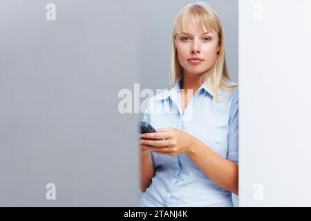 Femme d'affaires, smartphone et portrait en studio pour carrière d'entreprise avec les médias sociaux en maquette. Personne, fierté et visage avec téléphone portable et démarrage Banque D'Images