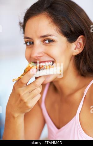 Pizza, manger et portrait de jeune femme pour le dîner, le déjeuner ou le souper avec une attitude positive. Heureux, sourire et personne féminine du Canada appréciant Banque D'Images