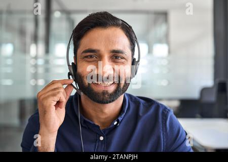 Homme indien souriant agent de centre d'appels portant le casque dans le bureau, portrait. Banque D'Images