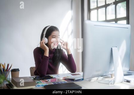 Graphiste femmes freelance portant casque à écouter de la musique à la détente après avoir esquissé la marque de logo et travailler à la conception sur le graphique Banque D'Images