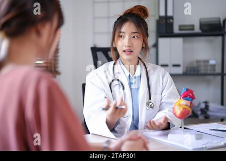 Cardiologue asiatique médecin femmes expliquant au sujet de l'anatomie du modèle cardiaque humain et donnant des conseils sur la thérapie médicale et mentale à la fema Banque D'Images