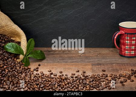 Kaffee Komposition mit Kaffeetasse, Kaffeebohnen in Kaffeesack, und Kaffeeblätter auf einem Holztisch, mit Raum für Text zum Beschriften Banque D'Images