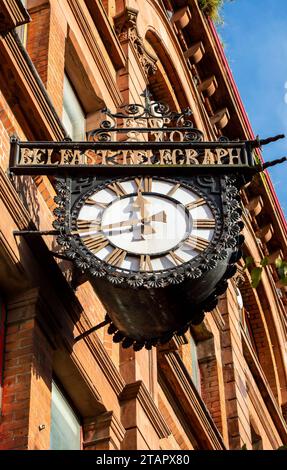 Belfast, Royaume-Uni, 29 septembre 2023. Vue vers le haut d'une grande horloge avec le logo du Belfast Telegraph et des bâtiments à Belfast dans une journée ensoleillée. Banque D'Images