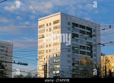 Gros plan d'une tour blanche soviétique illuminée par le soleil du soir et de nombreux fils électriques devant elle contre le ciel bleu Banque D'Images