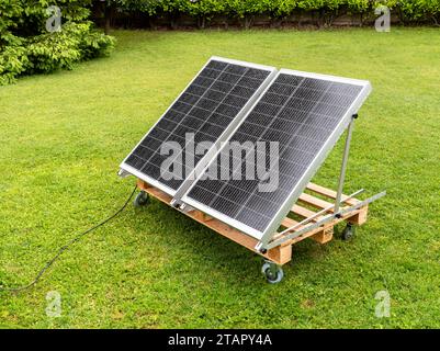 Panneaux photovoltaïques mouillés par la pluie sur la palette en bois dans le jardin de la maison. Concept d'énergie verte. Banque D'Images