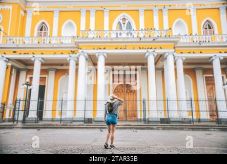 Vue arrière de la fille de touriste regardant la cathédrale. Femme touriste de dos regardant une cathédrale sur une place. Grenade, Nicaragua Banque D'Images
