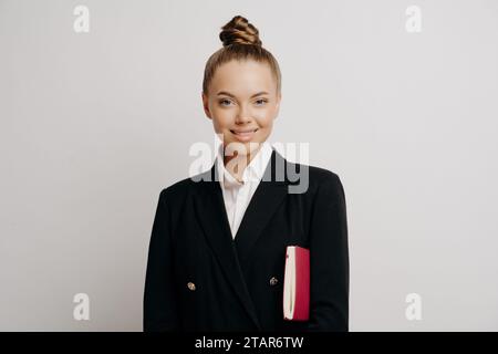 Assistant poli avec un sourire chaleureux, tenant un cahier, incarne l'efficacité et le soutien Banque D'Images