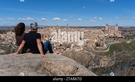 Un couple donne sur la ville historique de Tolède, un site du patrimoine mondial de l'UNESCO, assis sur la Piedra del Rey Moro, un point de vue bien connu sur la Banque D'Images