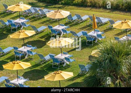 Parasols jaunes et chaises longues bleues sur Une pelouse dans un American Coastal Hotel Resort Banque D'Images