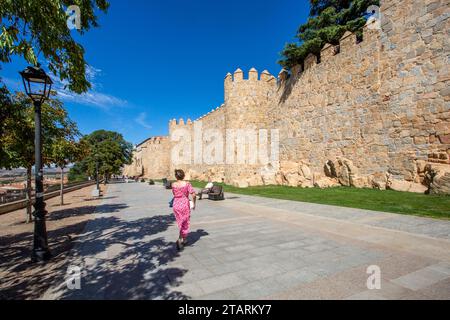 Femme marchant le long des remparts et fortifications dans la ville fortifiée espagnole d'Avila dans la communauté autonome de Castille-et-León Espagne Banque D'Images