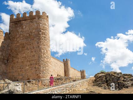 Femme marchant le long des remparts dans la ville médiévale fortifiée espagnole de Aliva capitale de la province espagnole d'Avila en Castille et León Espagne Banque D'Images