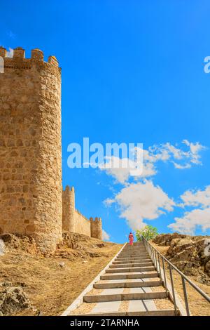 Femme marchant le long des remparts dans la ville médiévale fortifiée espagnole de Aliva capitale de la province espagnole d'Avila en Castille et León Espagne Banque D'Images