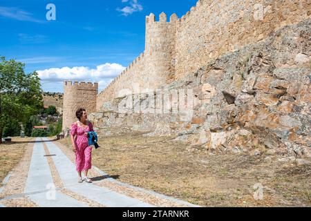 Femme marchant le long des remparts dans la ville médiévale fortifiée espagnole de Aliva capitale de la province espagnole d'Avila en Castille et León Espagne Banque D'Images