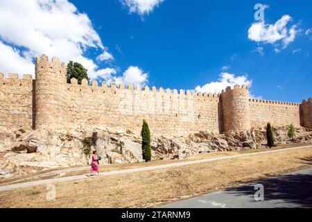 Femme marchant le long des remparts dans la ville médiévale fortifiée espagnole de Aliva capitale de la province espagnole d'Avila en Castille et León Espagne Banque D'Images